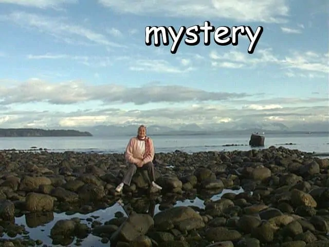 the word "mystery" with Marie sitting among the beach rocks