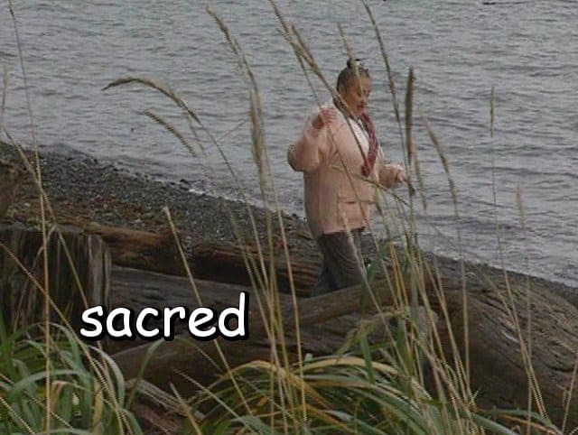 the word "sacred" with Marie walking behind some beach grass