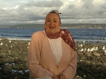 Marie smiling with delight on the beach with seagulls behind her.